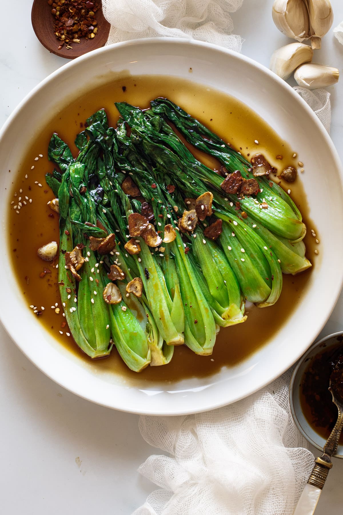 Pak choi with oyster sauce layered on a plate with garlic scattered over