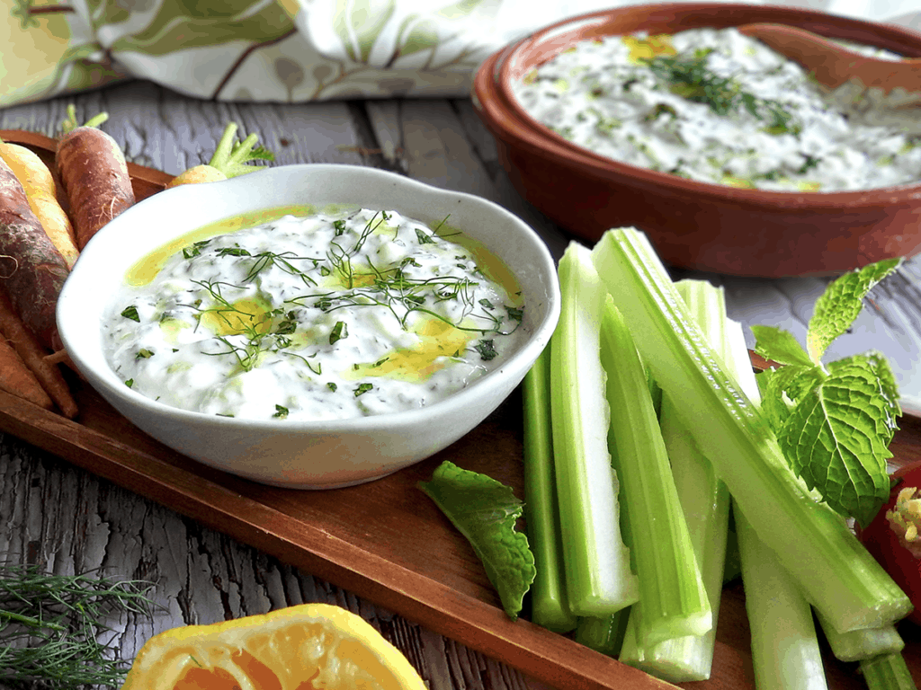 Homemade tzatziki on a board with vegetables