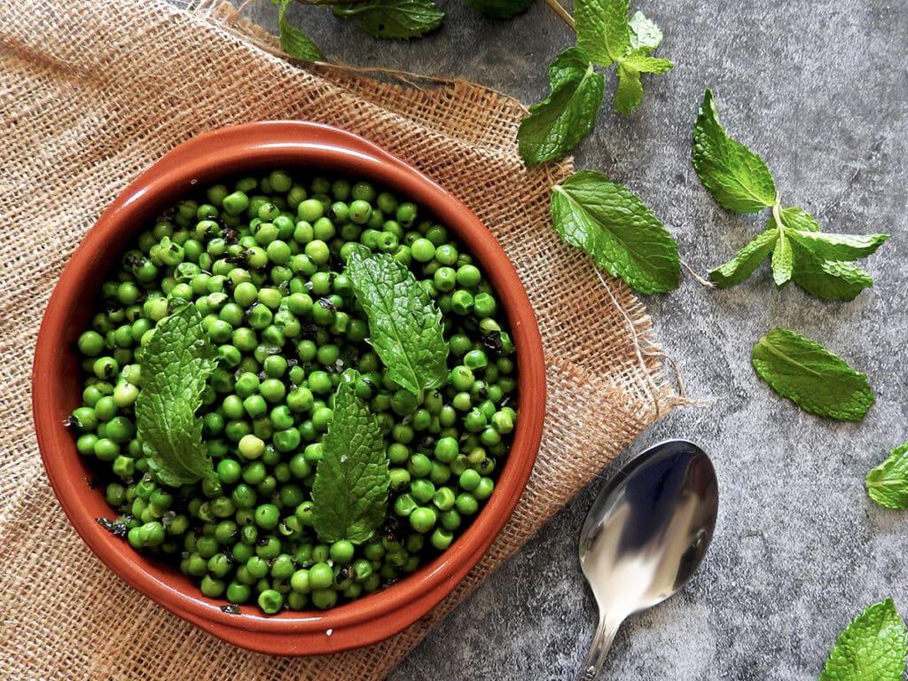Minted peas in a bowl with mint scattered around