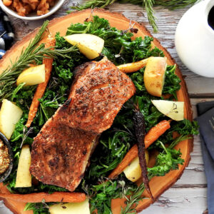Slow cooker pork belly on a wooden platter with kale and potatoes