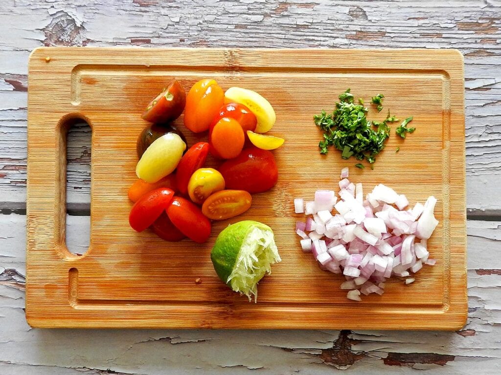 tomato and herb salsa ingredients prepared on a chopping board