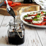 Balsamic glaze dripping off a spoon into a jar