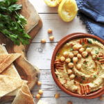 Hummus in a bowl garnished with paprika and chickpeas