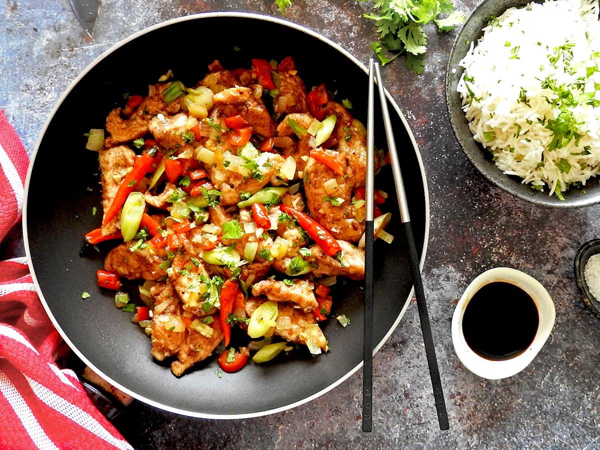 Salt and pepper chicken in a pan with rice