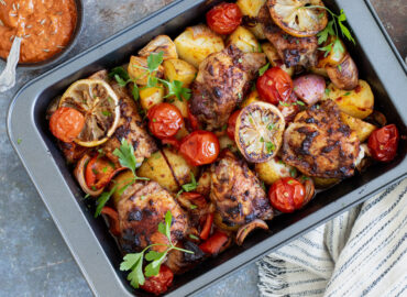 Harissa Chicken in a baking tray with a tea towel