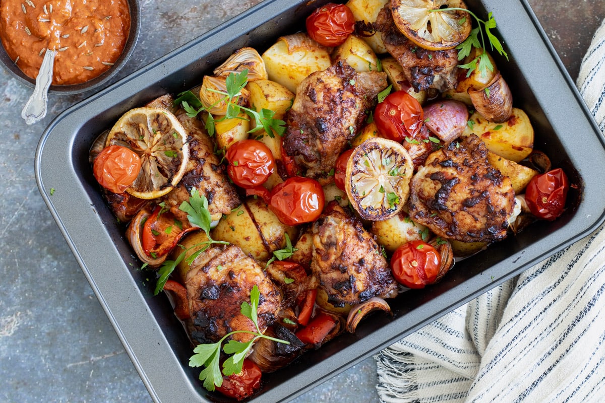 Harissa Chicken in a baking tray with a tea towel