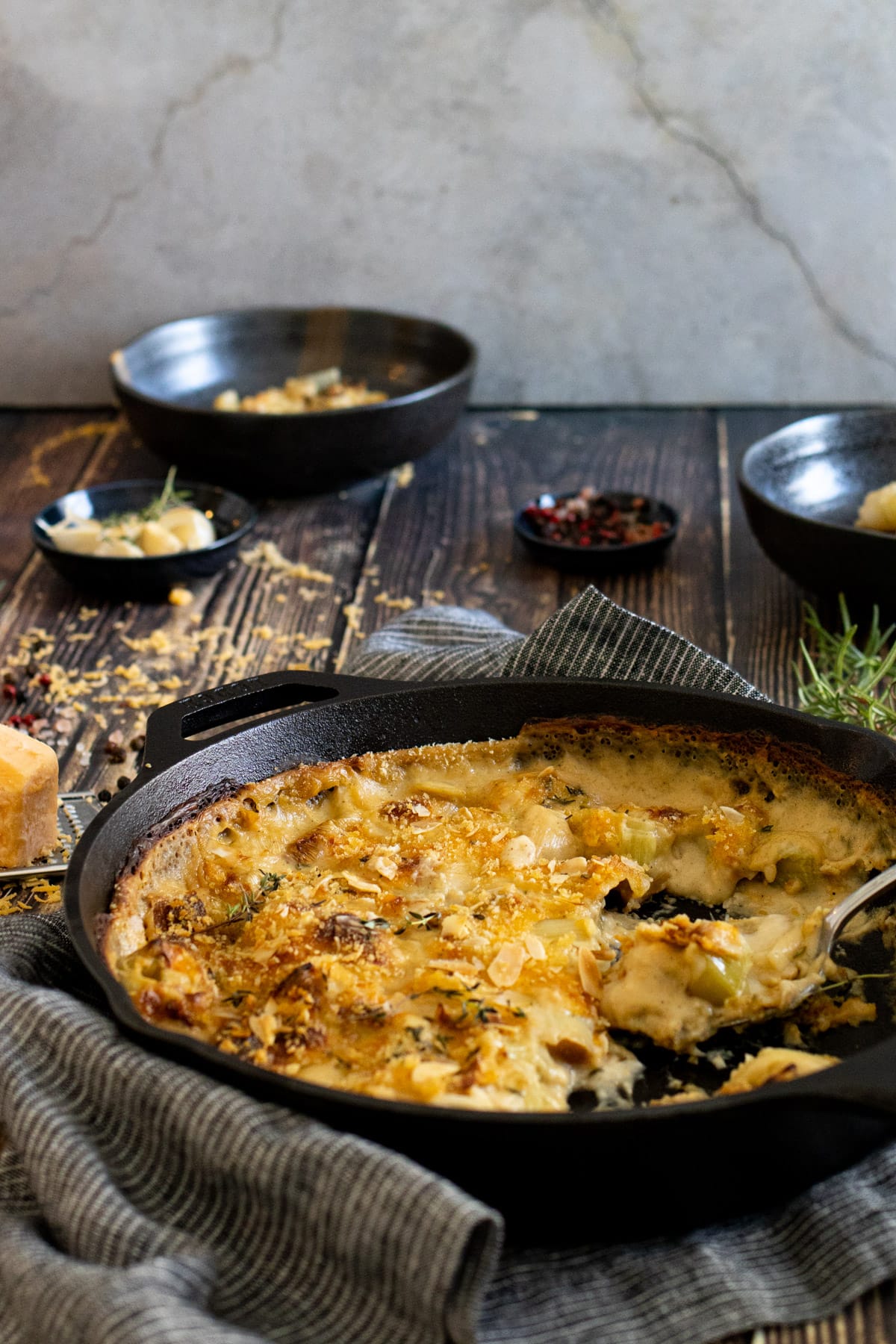 Cheesy leeks in a pan with bowls in the background