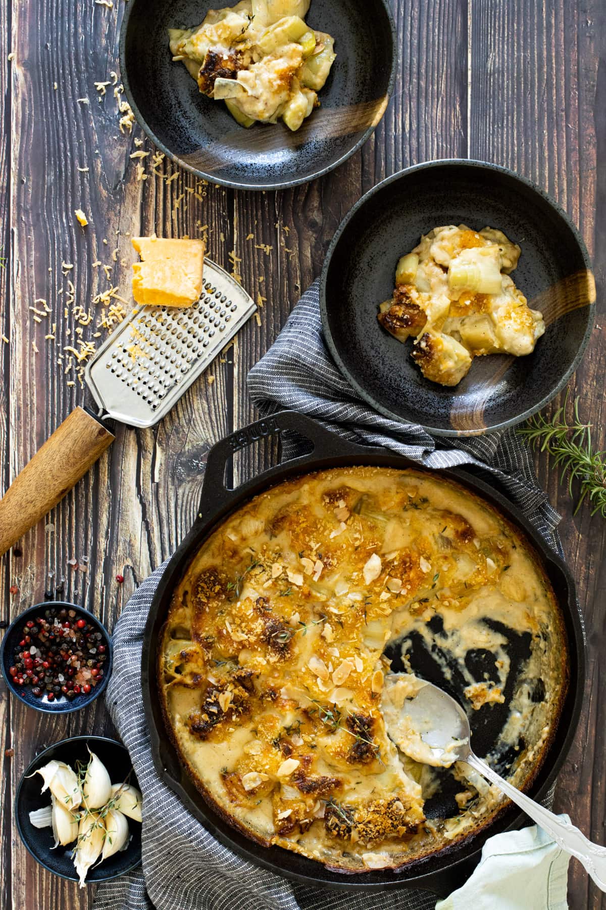 Cheesy leeks in a pan with grated cheese next to it