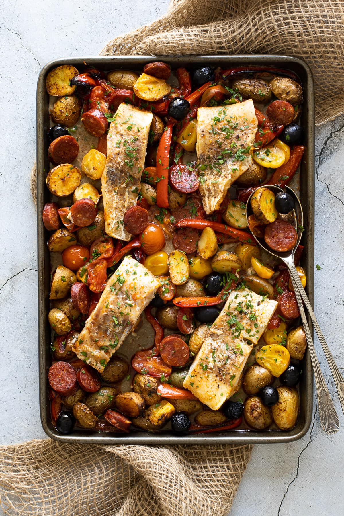 Cod and chorizo bake on a tray with serving spoon