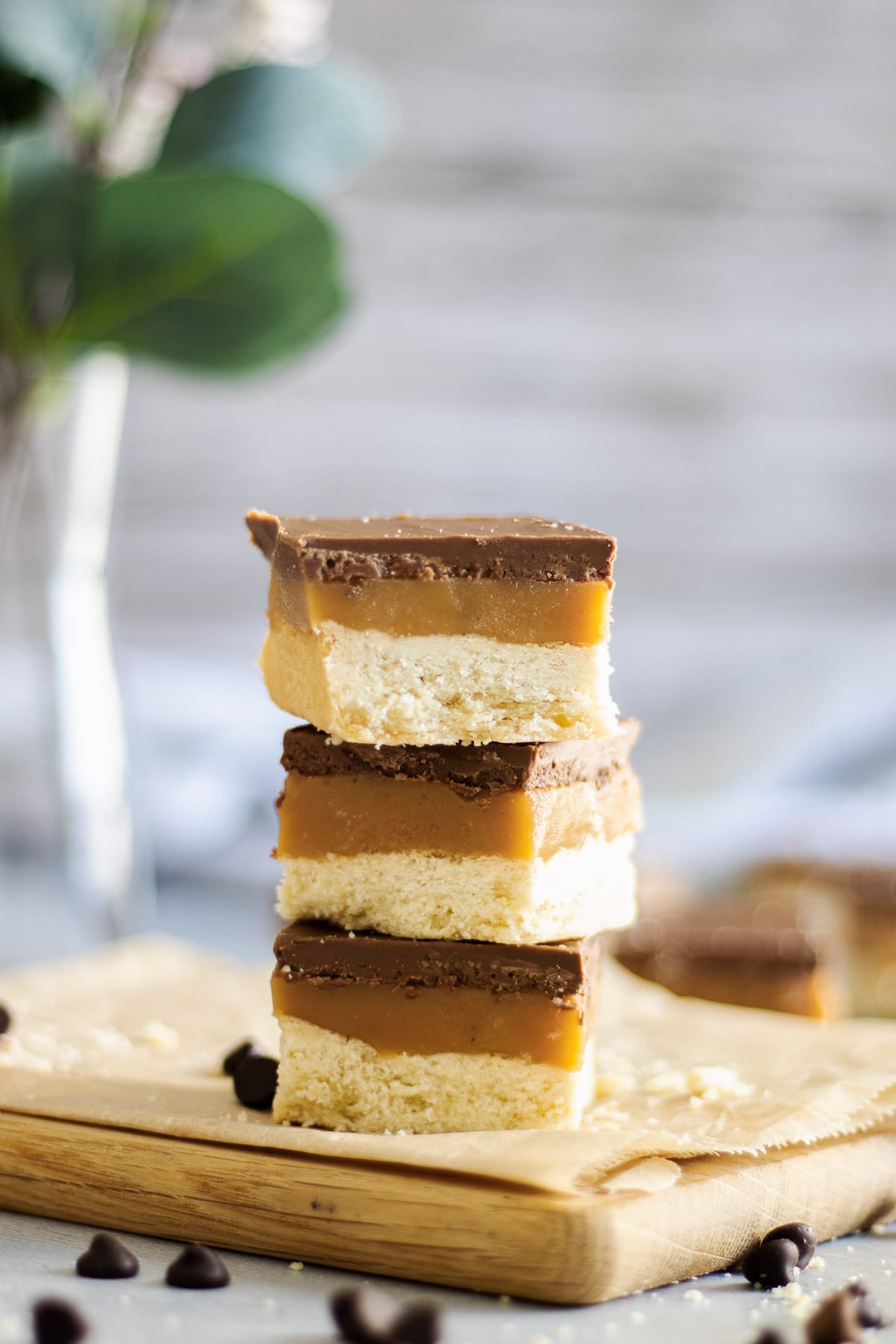 Three pieces of millionaire's shortbread stacked on a wooden board